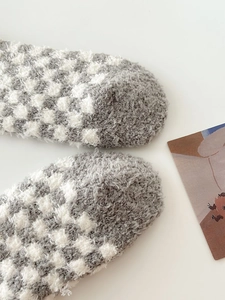 Detail of grey and white checkered coral fleece socks showing soft plush toe texture