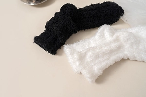 Detailed texture of black and white plush coral fleece socks for winter warmth