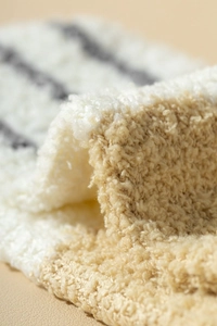Close-up of thick striped coral fleece fabric showing soft chenille texture and warm colors