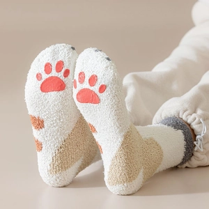 Detail of coral fleece cat claw socks showing red paw prints on non-slip soles