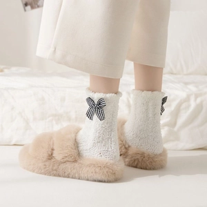 Detail of coral fleece socks with plaid bow decoration and plush slippers