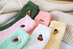 Macro detail of thick coral fleece socks featuring cute fruit embroidery on plush fabric
