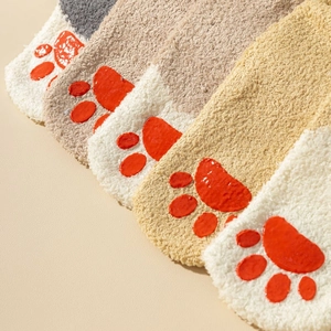 Macro detail of plush coral fleece socks with 3D red cat paw silicone anti-slip grips