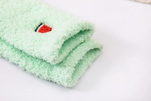 Detail of soft green coral fleece socks with cute red and green watermelon embroidery