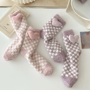 Pink and purple checkered coral fleece socks with 3D plush hearts in warm home setting