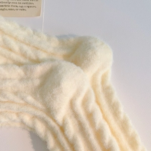 Close-up of cream white knitted thermal socks with soft fuzzy texture and ribbed pattern