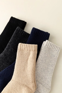 Close-up of five pairs of thick wool crew socks in neutral tones with ribbed cuffs