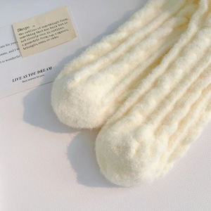 Detailed texture of thick cream white fuzzy socks with warm vertical knit pattern