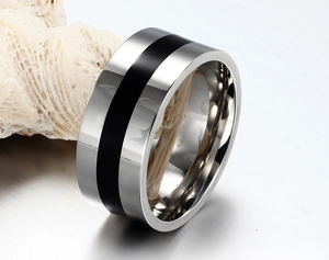 Macro shot of silver stainless steel ring with black enamel inlay on white coral base