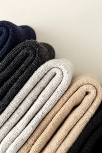 Close-up of thick wool knit socks stacked in navy, grey, oatmeal and black colors