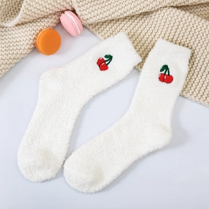 Cozy white coral fleece socks with red cherry embroidery on a warm knitted blanket