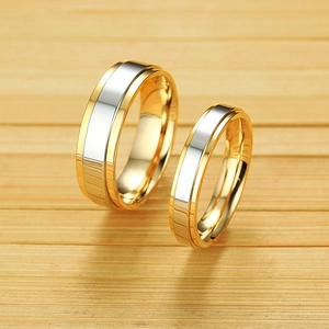 Polished two-tone gold and silver stainless steel couple rings on a bamboo mat