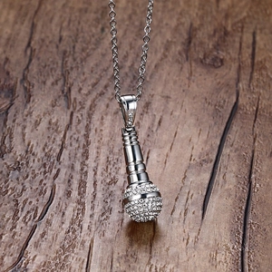 Détail macro du pendentif microphone argenté serti de strass blancs sur une chaîne argentée