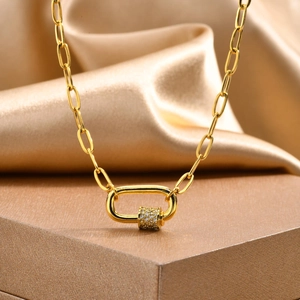 Macro view of gold paperclip chain necklace featuring a zircon carabiner lock pendant