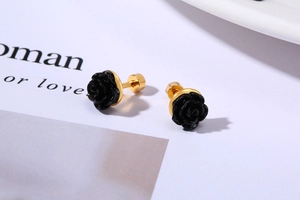 Close-up of black rose stud earrings featuring detailed petals and golden steel posts