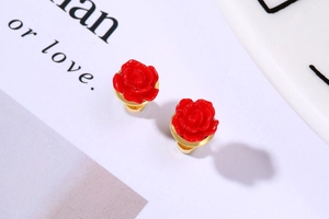 Detailed close-up of red rose titanium steel stud earrings with elegant gold base