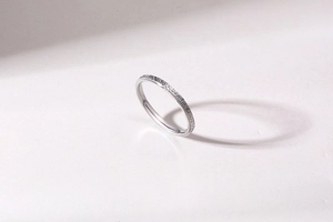 Close-up of a slim silver matte stainless steel ring with a textured frosted finish