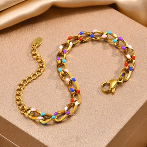 Macro detail of 18K gold chunky chain bracelet with colorful enamel charms on gift box