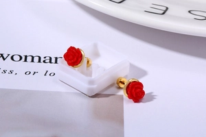 Detailed close-up of red rose stud earrings with layered petals and gold metal base
