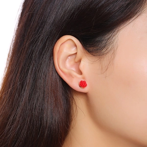 Detailed close-up of a red rose stud earring with fine petal texture worn by a model