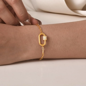 Close-up of a gold chain bracelet with a cubic zirconia-encrusted paperclip clasp detail
