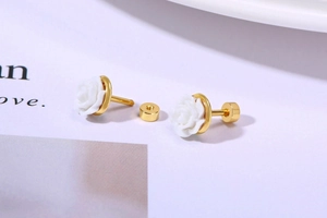 Detail view of white rose stud earrings with gold metal base and secure screw-back closure