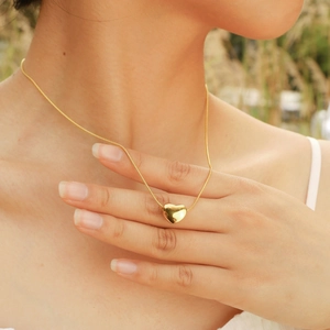 Collana con ciondolo a cuore in oro lucido su catena a serpente, mostrata su modella
