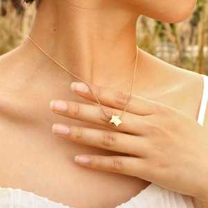 Gros plan d'un collier avec pendentif étoile dorée polie sur une chaîne serpent fine