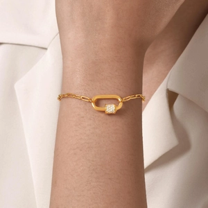 Close-up of a gold chain bracelet with a pavé zircon carabiner clasp on a model's wrist