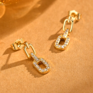 Detailed macro shot of gold rectangular drop earrings with shimmering pavé zircon stones