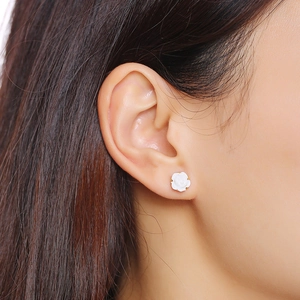 Detail view of a matte white rose stud earring on female model with delicate petal texture