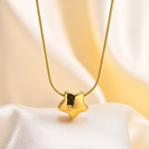 Macro d'un pendentif étoile dorée polie sur une chaîne serpent sur tissu en soie