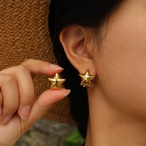 Boucles d'oreilles étoiles en or 18K en acier inoxydable portées avec un chapeau