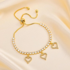 Detail of adjustable golden tennis bracelet with three cubic zirconia heart pendants