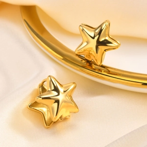 Détail de boucles d'oreilles étoiles dorées sur soie avec une finition miroir brillante