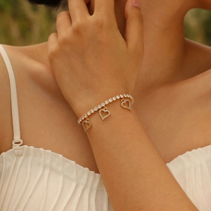 Close-up of a gold tennis bracelet with shimmering heart charms on a woman's wrist