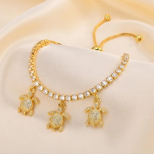 Detail of adjustable gold tennis bracelet featuring three crystal-encrusted turtle charms