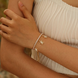 Detail of adjustable gold tennis bracelet featuring three crystal-paved turtle charms