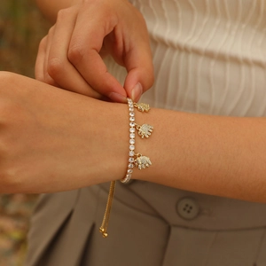 Detail of gold adjustable tennis bracelet with zircon stones and small elephant charms