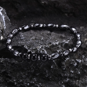 Men's minimalist beaded bracelet with faceted hematite and agate on dark rock background