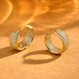 Close-up of gold-plated C-shaped earrings with multi-row pave-set cubic zirconia