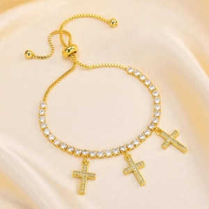 Macro detail of gold-plated tennis bracelet with three cross charms and cubic zirconia