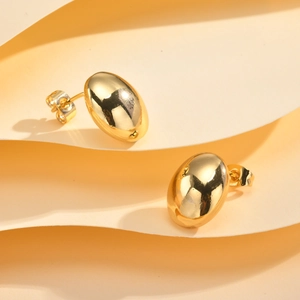 Vue détaillée des boucles d'oreilles ovales dorées polies sur papier texturé