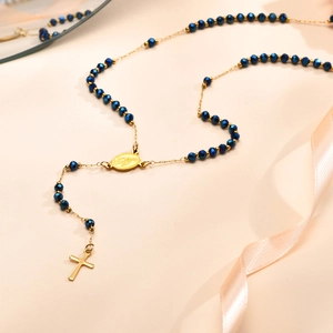 Details von blauen Kristallperlen und goldenem Jungfrau Maria Emblem an der Rosenkranzkette