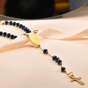 Makro-Detail der goldenen Maria-Medaille und blauen Perlen auf der Kreuzkette