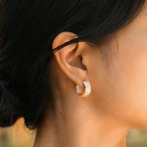 Close-up of a gold-plated C-shaped hoop earring with shimmering pavé zircon stones