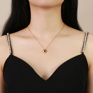 Élégant collier pendentif cœur doré avec pierre d'onyx noire porté par un mannequin