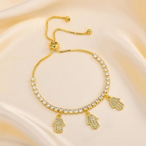 Detail of gold Hamsa hand charm bracelet with sparkling zircons on champagne silk