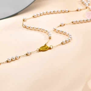 Detail der goldenen Marienmedaille und weißen Perlen an einer religiösen Rosenkranzkette