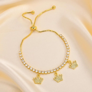Detail of adjustable gold slider bracelet with sparkling zircons and crown charms